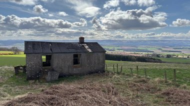 Countryside landscape near Milquhanzie Hill in Perth and Kinross Scotland showing ridge summit with masts, walking paths, and nearby ancient standing stones.