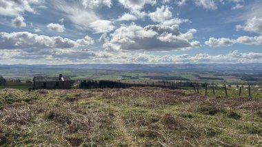 Countryside landscape near Milquhanzie Hill in Perth and Kinross Scotland showing ridge summit with masts, walking paths, and nearby ancient standing stones.