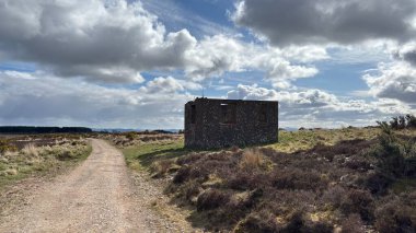 Countryside landscape near Milquhanzie Hill in Perth and Kinross Scotland showing ridge summit with masts, walking paths, and nearby ancient standing stones.
