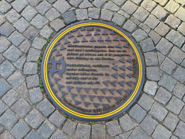 İsveç: Malm şehir merkezindeki kaldırımlı caddede insan deliği kapağı modern mimari ve canlı sokak hayatının bir karışımını sergiliyor.