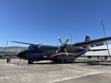 Airbus A400M Atlas 'ın Toulouse, Fransa' daki Aeroscopia Müzesi 'nin dışındaki ilk prototip F-WMT prototipi uçak gövdesi, kanat açıklığı, pervaneler, iniş takımları ve müze cephesine karşı kargo kapısı olan yüksek kanatlı turbo pervaneli askeri hava aracını gösteriyor..