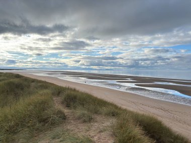 Sandy Aberlady Körfezi plajı. Doğu Lothian doğasında Firth of Forth nehri kıyısında. Uzak Forth Bridges ve Fife sahilleri bulutlu gökyüzü altında..