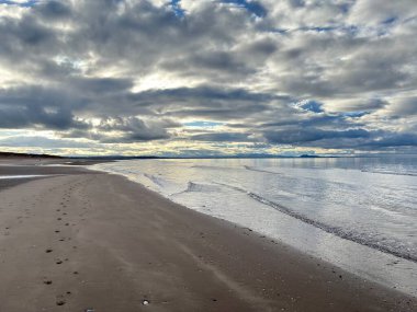 Sandy Aberlady Körfezi plajı. Doğu Lothian doğasında Firth of Forth nehri kıyısında. Uzak Forth Bridges ve Fife sahilleri bulutlu gökyüzü altında..