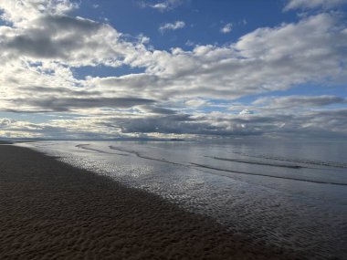 İskoçya 'daki Aberlady Körfezi' ndeki geniş kumlu sahil kum tepecikleri ve kıyıda hafif dalgalarla ovalanan ve haliçlerin üzerinde açık gökyüzü.