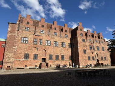 Malmhus Şatosu 'nun dış görünüşü, Malm İsveç' in İskandinavya 'daki en eski korunmuş Rönesans kalesi, taş cephe duvarları silindirik duvarlar, siperler, kemerli pencereler, kuru hendek erişim köprüsü bayrak direği ve bitişik park.