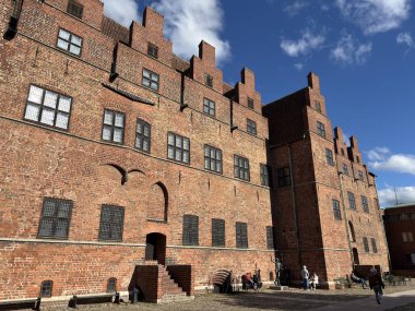 Malmhus Şatosu 'nun dış görünüşü, Malm İsveç' in İskandinavya 'daki en eski korunmuş Rönesans kalesi, taş cephe duvarları silindirik duvarlar, siperler, kemerli pencereler, kuru hendek erişim köprüsü bayrak direği ve bitişik park.