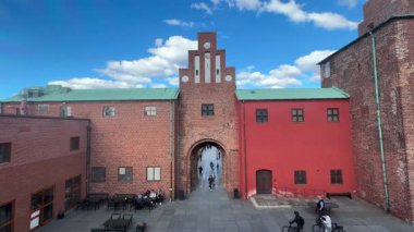 Malmhus Şatosu 'nun dış görünüşü, Malm İsveç' in İskandinavya 'daki en eski korunmuş Rönesans kalesi, taş cephe duvarları silindirik duvarlar, siperler, kemerli pencereler, kuru hendek erişim köprüsü bayrak direği ve bitişik park.