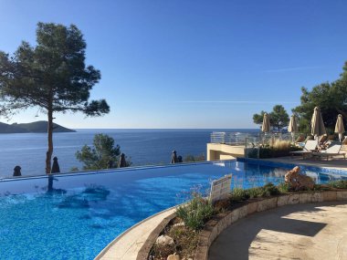 Yunanistan 'ın Korfu kentindeki Palaiokastritsa kentinin kıyı tepeleri, zeytin ağaçları, kayalık arazi ve adanın tipik Akdeniz bitkilerine sahip manzarası.