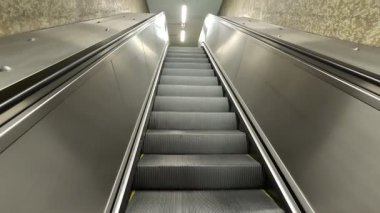 Portekiz, Lizbon 'da, derin yeraltı metro istasyonundan beyaz kiremitli duvarlar, tırabzanlar ve tepe ışıkları ile sokak çıkışına doğru yükselen uzun yürüyen merdivene bakın..