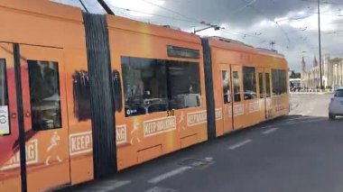 Lizbon, Portekiz 'de şehir sokaklarında hareket halindeki modern eklemli tramvayın dış görünüşü, geçen binalar, trafik ve kentsel çevre güzergahı boyunca.