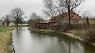 Elblag 'da yağmur kanalı, tarihi bölge yakınlarındaki şehir merkezinde bulutlu gökyüzü altındaki binalar ve ağaçlarla çevrili..