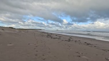 Fırtınalı bir günde İngiltere 'nin Northumberland kentindeki Bamburgh yakınlarındaki Ross Sands plajında dalgalı dalgalarla dalgalı deniz ve kara bulutlar..
