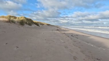 Fırtınalı bir günde İngiltere 'nin Northumberland kentindeki Bamburgh yakınlarındaki Ross Sands plajında dalgalı dalgalarla dalgalı deniz ve kara bulutlar..
