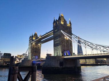 Londra, İngiltere 'deki Thames nehrinin üzerinde geceleyin aydınlanan Tower Bridge' de baskül açıklığı, asma kablolar, neo-gotik kuleler ve üst düzey yürüyüş yolları yer alıyor..