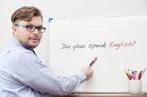 Молодой кавказский учитель указывает на титул Вы говорите по-английски? — стоковое фото