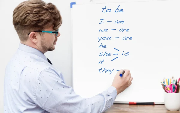 Genç öğretmen markerboard üzerinde İngilizce Dilbilgisi yazma