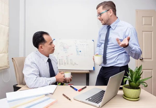 Two businessmen asian and caucasian enjoy coffee in office — Stock Photo, Image