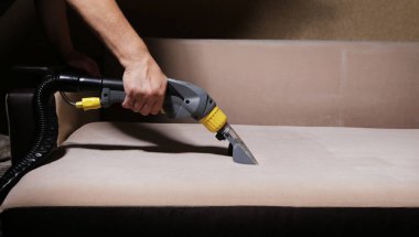 Kanepeyi elektrikli süpürgeyle temizliyorum.