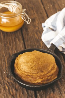 Delicious  pancakes  on pan, honey  on the table 