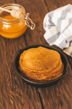 Delicious  pancakes  on pan, honey  on the table 