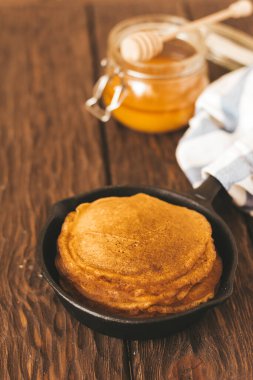 Delicious  pancakes  on pan, honey  on the table 