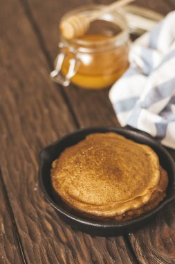 Delicious  pancakes  on pan, honey  on the table 