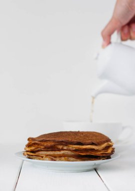 Delicious  pancakes on the table. person pouring tea 