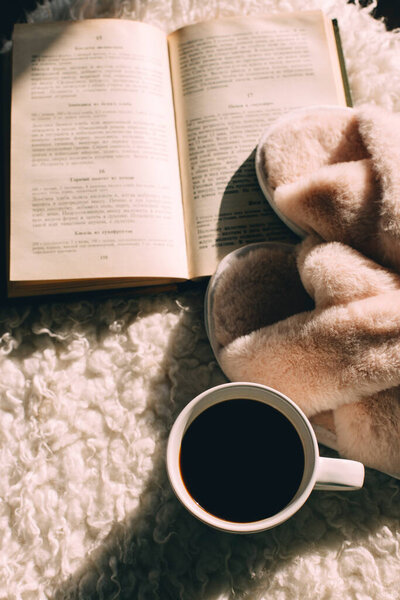 концепция уютного дома, кофе, тапочки и книга 