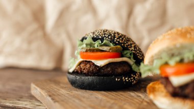 Ahşap arka planda etli, domatesli ve peynirli burger.