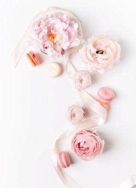 Beyaz zemin üzerinde güller olan pembe badem kurabiyelerinin üst görünümü  
