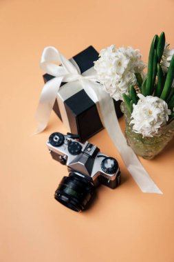 Hediye kutusunun yakın plan görüntüsü, bir buket çiçek ve pembe arka planda bir kamera.