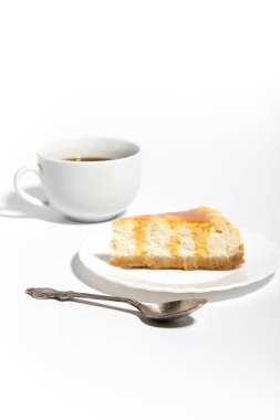 Beyaz arka planda bir fincan kahveli lezzetli peynirli kek.