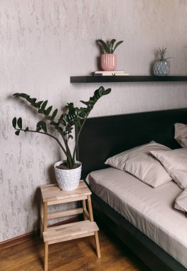 Yatak odasının içinde siyah yatak, beyaz çarşaf ve yastıklar var.