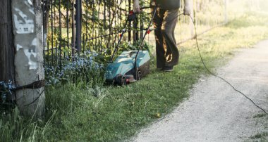 Yazın çim biçme makinesiyle çim biçen adam.