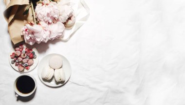 Bir fincan kahve, böğürtlen, badem kurabiyesi ve şakayık çiçekleri.