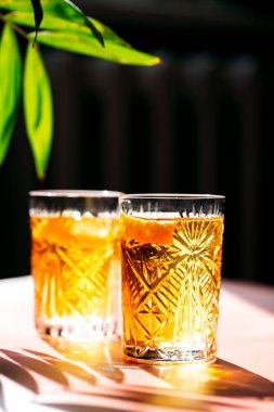 Pembe arka planda limonlu soğuk limonata ve güneş ışınları.