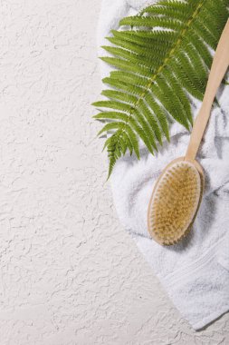 Beton arka planda havlu ve yaprak ile vücut masajı fırçası
