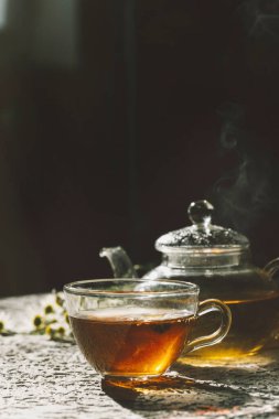 Koyu arkaplanda cam çaydanlık ile sıcak çay.