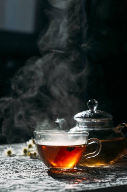 Koyu arkaplanda cam çaydanlık ile sıcak çay.