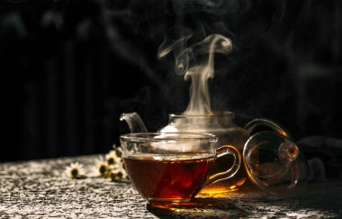 Koyu arkaplanda cam çaydanlık ile sıcak çay.