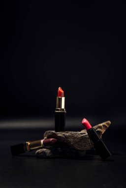 Taşlardaki rujlar, siyah arkaplanda kozmetik ürünler.