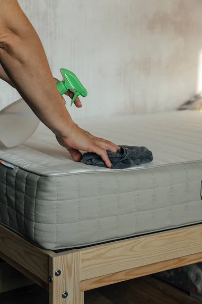 woman cleaning mattress with the rag, close-up view