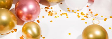 Beyaz arka planda konfetileri ve simleri olan altın balonlar.