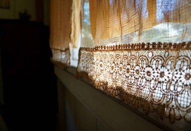 Hassas sabah güneşini içeri alan perdeli klasik bir pencere.