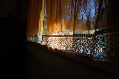 Hassas sabah güneşini içeri alan perdeli klasik bir pencere.