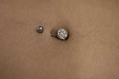 Bir kadının göbeğine piercingle yakın çekim.