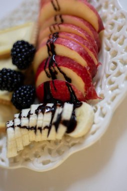 Bir muz ve bir elma dilimlenmiş ve çikolata şurubuyla kaplanmış.