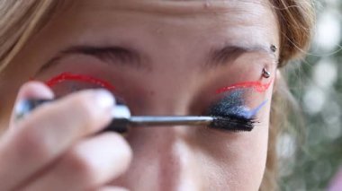 Kirpiklerine rimel süren beyaz bir kız, kaş delici ve kahverengi gözlü..