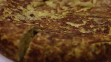 Geleneksel İspanyol patates omletini dilimlemek. Lezzetli İspanyol patates omleti beyaz bir tabakta bıçakla kesiliyor.