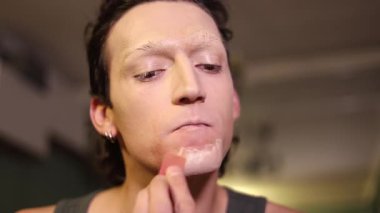 Millennial Man bir gösteri veya sürükleme performansı için hazırlanırken süngerle temeli uyguluyor